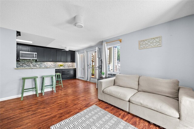 living room with dark wood-style floors, a ceiling fan, and a textured ceiling