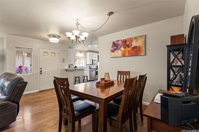 dining space with baseboards, a chandelier, and wood finished floors