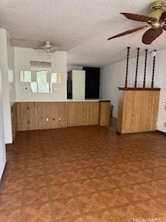spare room with a textured ceiling, ceiling fan, and wood walls