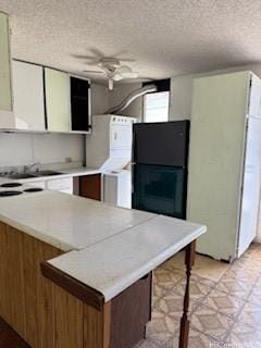 kitchen with ceiling fan, light floors, light countertops, freestanding refrigerator, and a textured ceiling