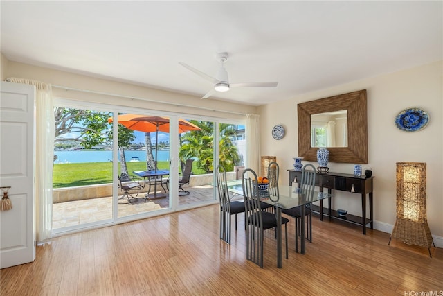 215 Koko Isle Cir Unit 5502, Honolulu, HI 96825 - dining area featuring a water view, a ceiling fan, light wood-type flooring, and baseboards
