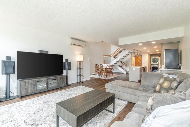 217 Prospect St Unit 106, Honolulu, HI 96813 - living room featuring stacked washer and clothes dryer, a wall mounted air conditioner, stairway, wood finished floors, and a textured ceiling