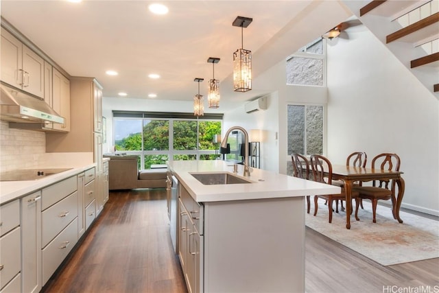 kitchen featuring a wall mounted AC, under cabinet range hood, a sink, black electric stovetop, and gray cabinets