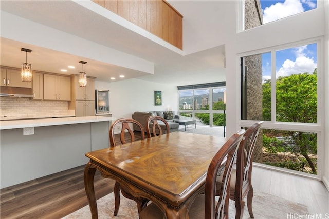 dining area with a high ceiling, recessed lighting, and wood finished floors