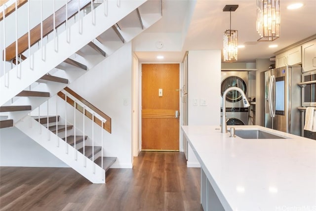kitchen featuring light countertops, a sink, decorative light fixtures, and dark wood-style floors