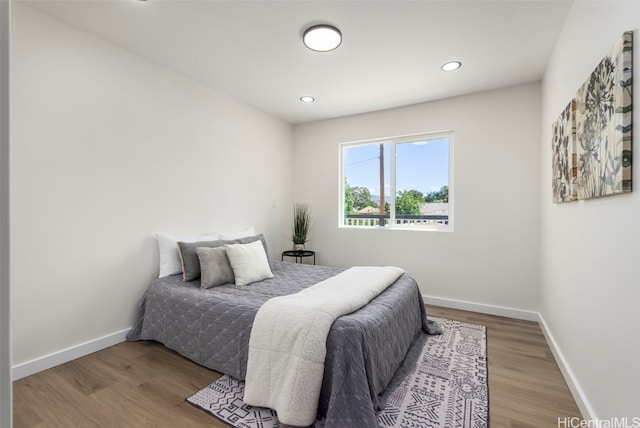 bedroom with baseboards, wood finished floors, and recessed lighting