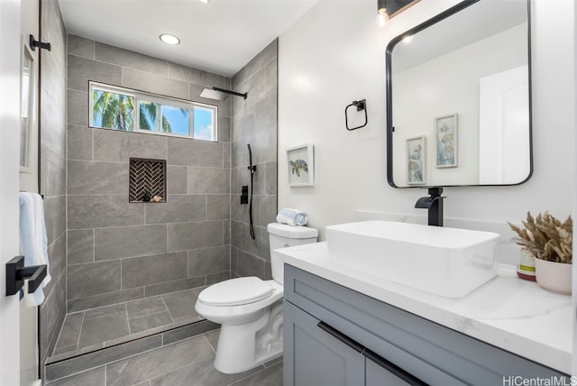 full bathroom featuring toilet, recessed lighting, tiled shower, and vanity