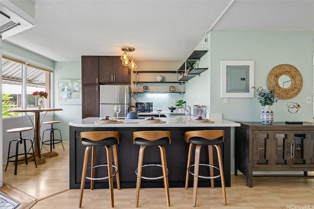 1330 Wilder Ave Unit 310, Honolulu, HI 96822 - kitchen featuring freestanding refrigerator, electric panel, a textured ceiling, dark brown cabinetry, and light wood-style floors