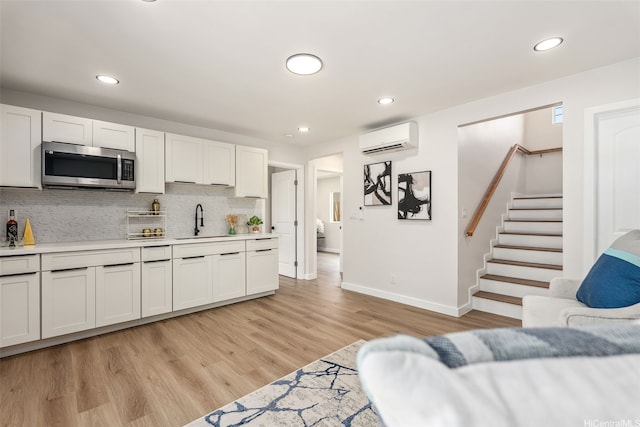 84-1001 Lahaina St Unit 1, Waianae, HI 96792 - kitchen featuring stainless steel microwave, a wall mounted air conditioner, light countertops, backsplash, and a sink