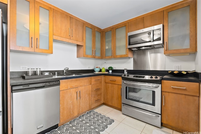 1009 Kapiolani Blvd Unit 3708, Honolulu, HI 96814 - kitchen with appliances with stainless steel finishes, glass insert cabinets, light tile patterned flooring, dark countertops, and brown cabinets
