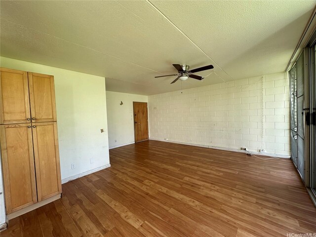 95-017 Kuahelani Ave Unit 124, Mililani, HI 96789 - unfurnished bedroom featuring dark wood-style flooring, a textured ceiling, concrete block wall, a ceiling fan, and baseboards