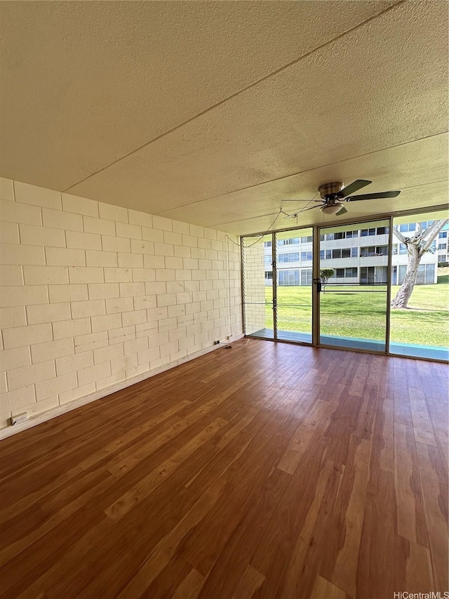 95-017 Kuahelani Ave Unit 124, Mililani, HI 96789 - unfurnished room with ceiling fan, dark wood-style flooring, concrete block wall, and a textured ceiling