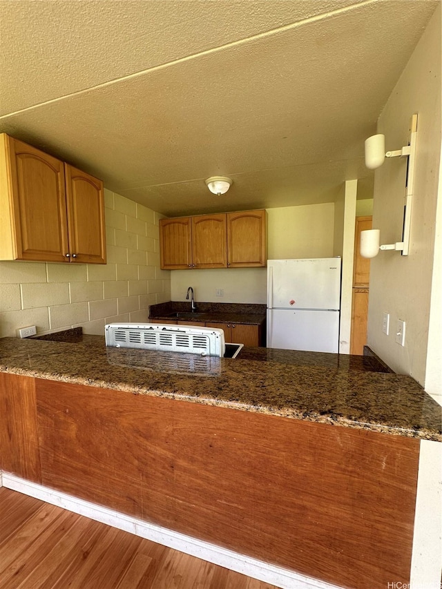 95-017 Kuahelani Ave Unit 124, Mililani, HI 96789 - kitchen with freestanding refrigerator, a peninsula, dark stone counters, and a textured ceiling