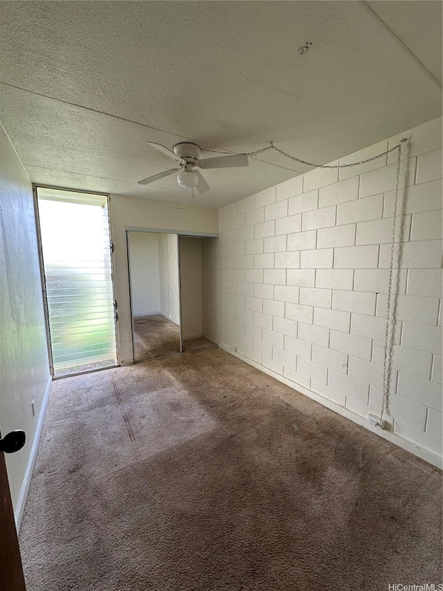 95-017 Kuahelani Ave Unit 124, Mililani, HI 96789 - unfurnished bedroom featuring concrete block wall, carpet, a closet, a textured ceiling, and ceiling fan