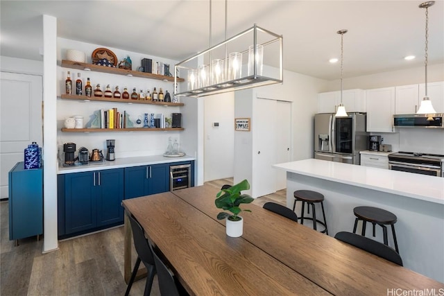 kitchen with a kitchen bar, wine cooler, stainless steel appliances, open shelves, and blue cabinets