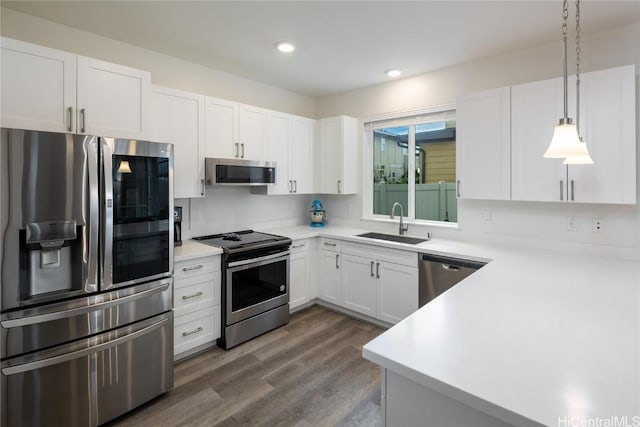 kitchen featuring light countertops, stainless steel appliances, a sink, white cabinets, and wood finished floors