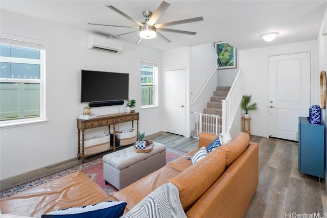 living room featuring a ceiling fan, a wall unit AC, stairs, and wood finished floors