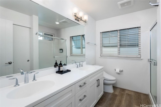 bathroom featuring toilet, a sink, a stall shower, and wood finished floors