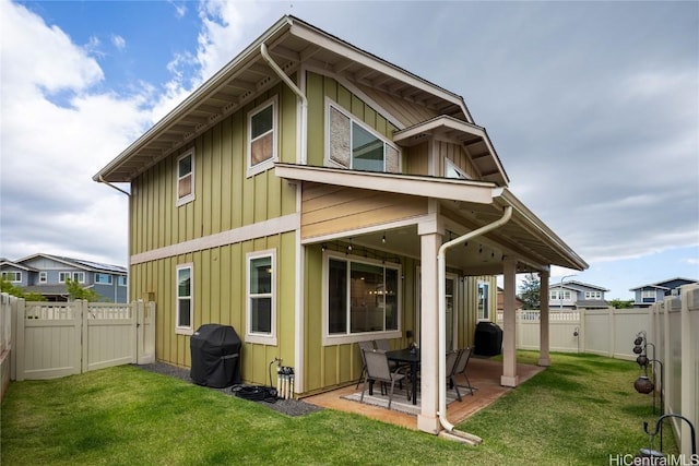 back of house featuring a patio, board and batten siding, and a yard