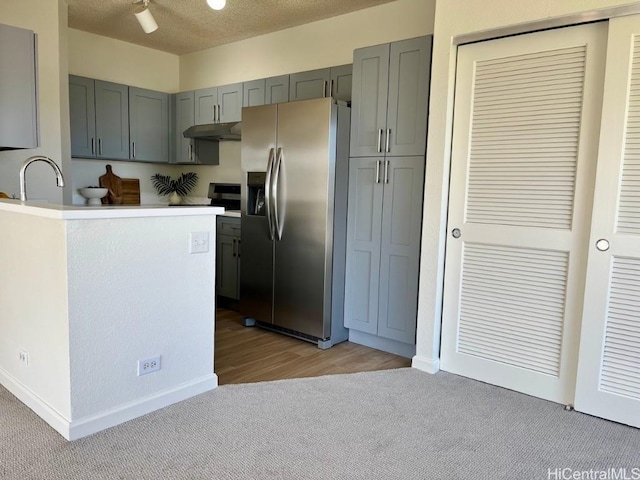 91-495 Puamaeole St Unit 38R, Ewa Beach, HI 96706 - kitchen with light carpet, stainless steel fridge with ice dispenser, gray cabinets, and under cabinet range hood