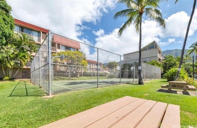 view of tennis court with community basketball court, fence, and a yard