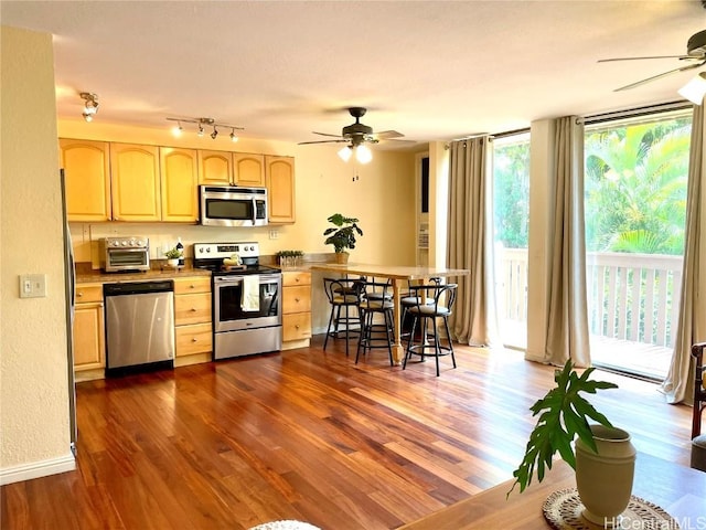 kitchen featuring light brown cabinetry, dark wood-type flooring, a toaster, ceiling fan, and appliances with stainless steel finishes