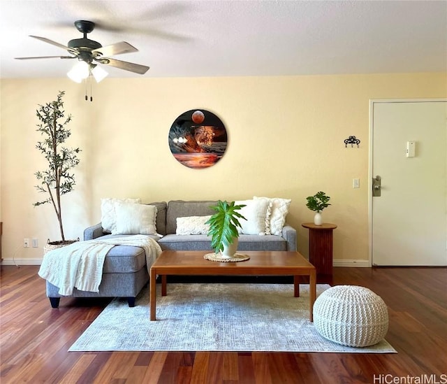 living area with baseboards, wood finished floors, and a ceiling fan