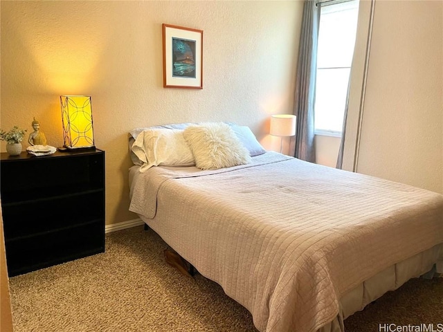 carpeted bedroom featuring a textured wall and multiple windows