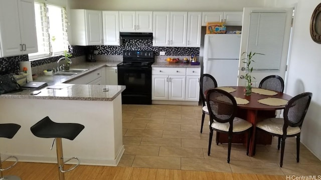 36 Ilima St, Wahiawa, HI 96786 - kitchen with black range with electric stovetop, under cabinet range hood, freestanding refrigerator, white cabinets, and decorative backsplash