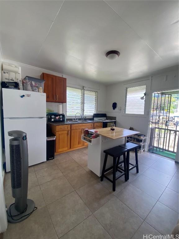 kitchen featuring freestanding refrigerator, a sink, plenty of natural light, and a breakfast bar