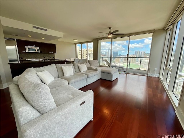 living area with visible vents, a city view, a wall of windows, ceiling fan, and dark wood-type flooring