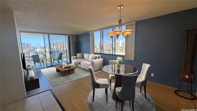 dining space with a skyline view, a chandelier, wood finished floors, a wall of windows, and a textured ceiling