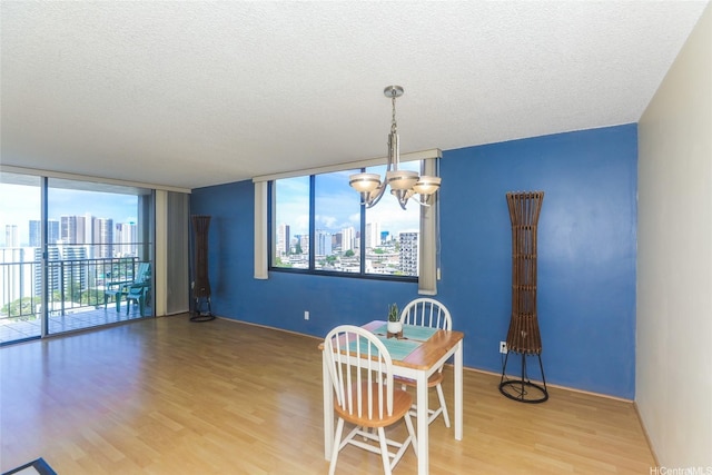 dining area featuring wood finished floors, a chandelier, a city view, and a textured ceiling