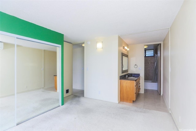 unfurnished bedroom with a sink, light colored carpet, a closet, and connected bathroom