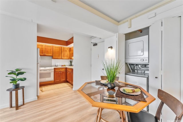 dining area featuring baseboards, light wood finished floors, and stacked washer / drying machine
