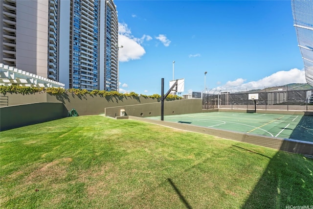 view of basketball court featuring a lawn, community basketball court, and fence