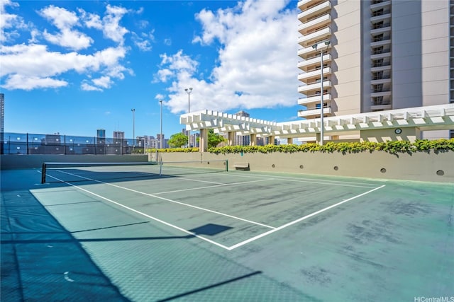 view of tennis court featuring fence and a city view