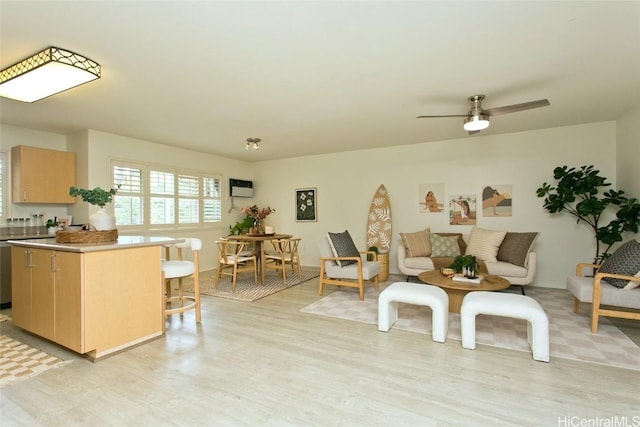 living area with an AC wall unit, light wood-type flooring, and ceiling fan