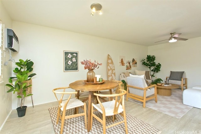 dining room featuring a ceiling fan, light wood finished floors, and a wall mounted air conditioner