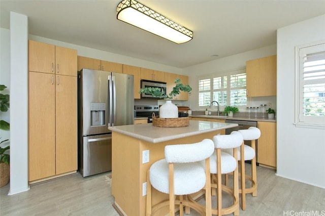 kitchen featuring light wood-style floors, a kitchen breakfast bar, a center island, light countertops, and stainless steel appliances