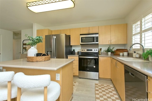 kitchen featuring light countertops, light brown cabinets, a sink, and stainless steel appliances