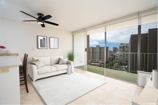 living area with a city view, expansive windows, ceiling fan, and tile patterned flooring