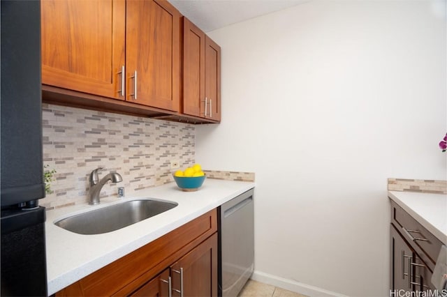 kitchen featuring light countertops, a sink, stainless steel dishwasher, brown cabinetry, and decorative backsplash