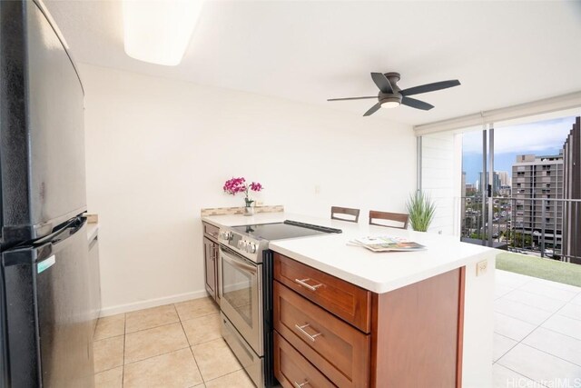kitchen featuring a ceiling fan, freestanding refrigerator, stainless steel range with electric stovetop, brown cabinetry, and a view of city