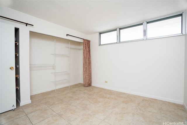 unfurnished bedroom featuring a closet, baseboards, and light tile patterned floors