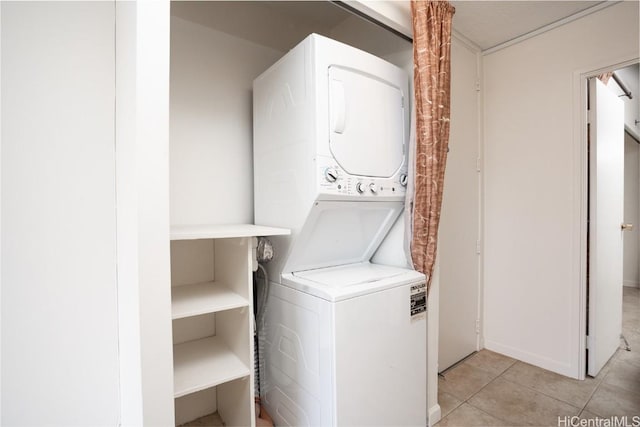 laundry area featuring light tile patterned floors, stacked washing maching and dryer, and laundry area