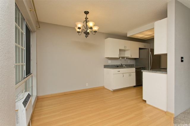 kitchen with a notable chandelier, white cabinetry, light wood-style floors, and a sink
