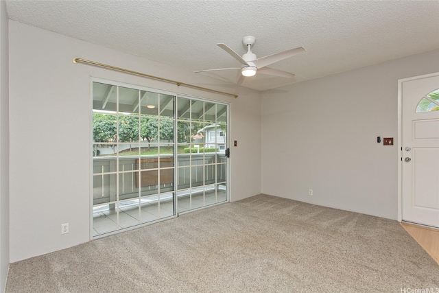 carpeted spare room with a ceiling fan and a textured ceiling