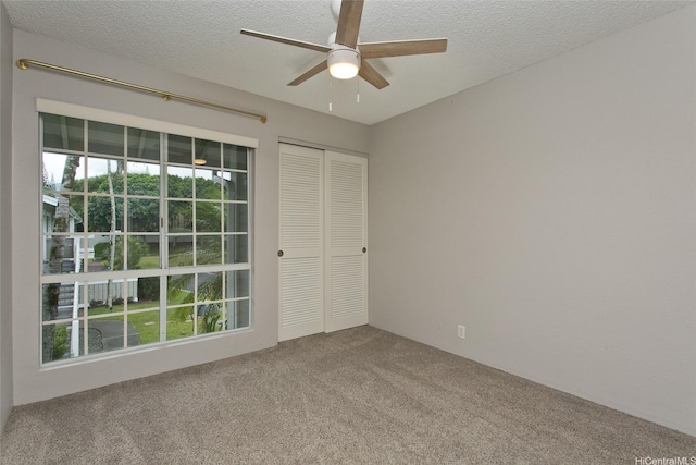 carpeted empty room with a ceiling fan and a textured ceiling