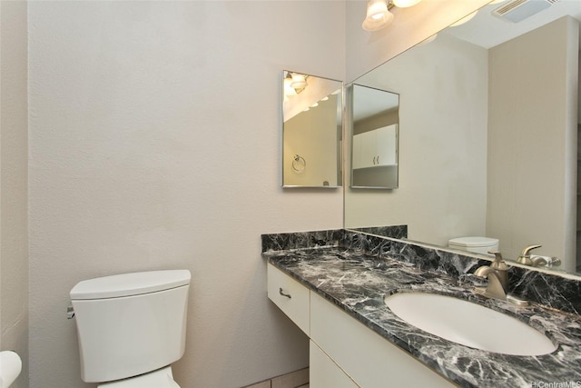 half bathroom featuring toilet, vanity, and visible vents